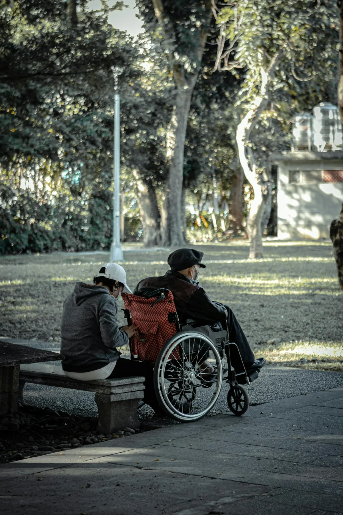 Deux personnes échangeant en extérieur, dont une en fauteuil roulant