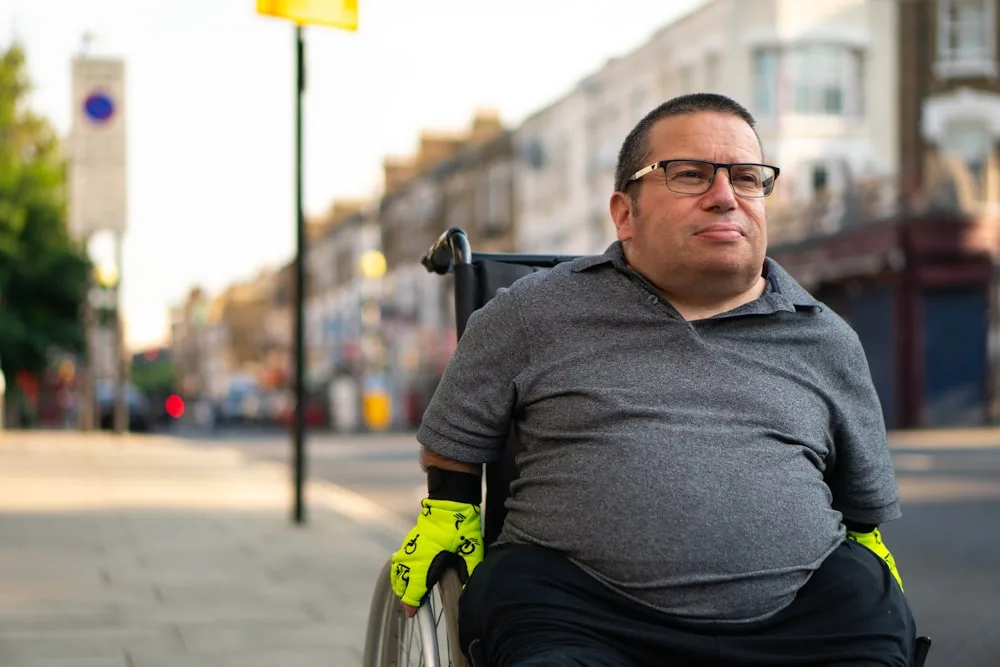 Un homme en fauteuil roulant, souriant, dans une rue de ville